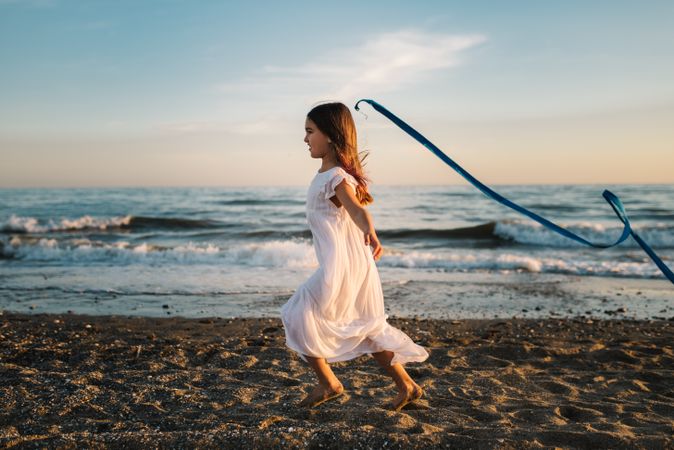 Adorable girl playing with ribbon on seaside