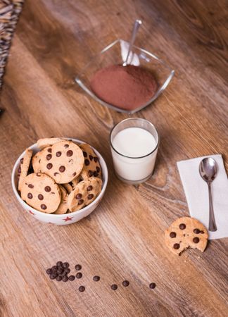 Chocolate chip cookies and milk on wood background