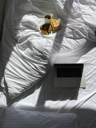 Plate of crepes in bed with coffee and laptop