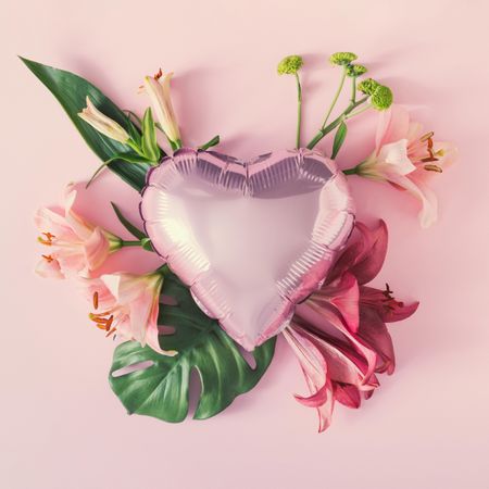 Pink heart balloon surrounded with pink spring flowers