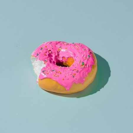 Pink glazed donut on blue pastel background