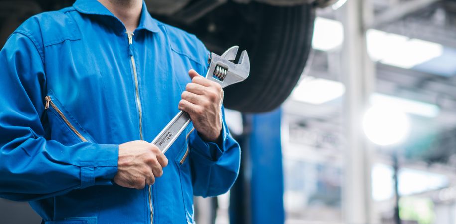 Banner of white male mechanic holding wrench at auto garage