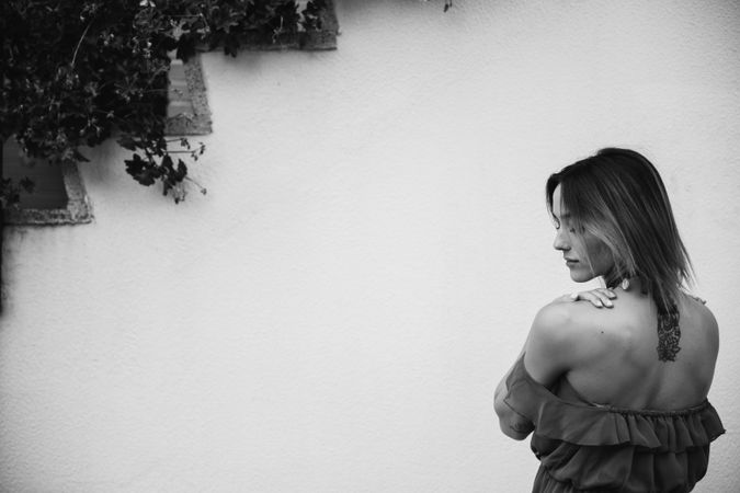 Barefoot woman leaning on house wall