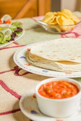 Traditional mexican food with a plate of tortillas, fresh salad, nachos and a bowl of spicy sauce