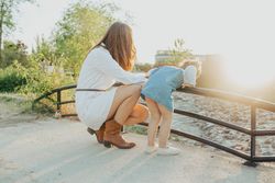 Anonymous mother and daughter looking at river in park