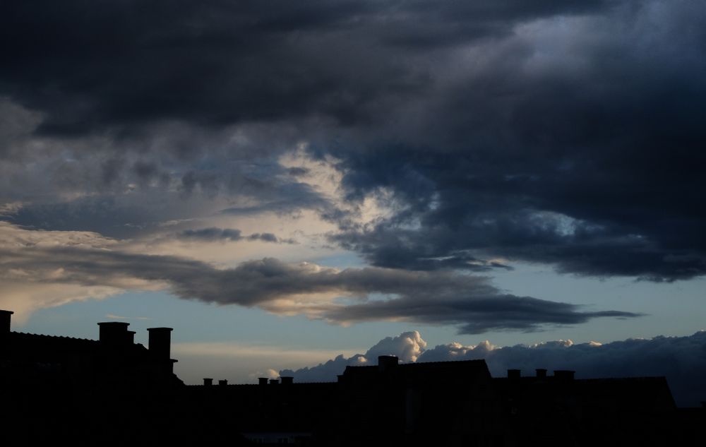 Blue sky with clouds over houses in the shadows