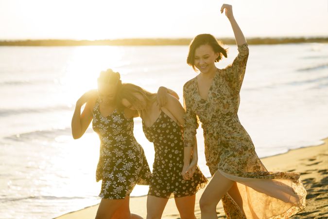 Three happy women skipping towards the coast on beach