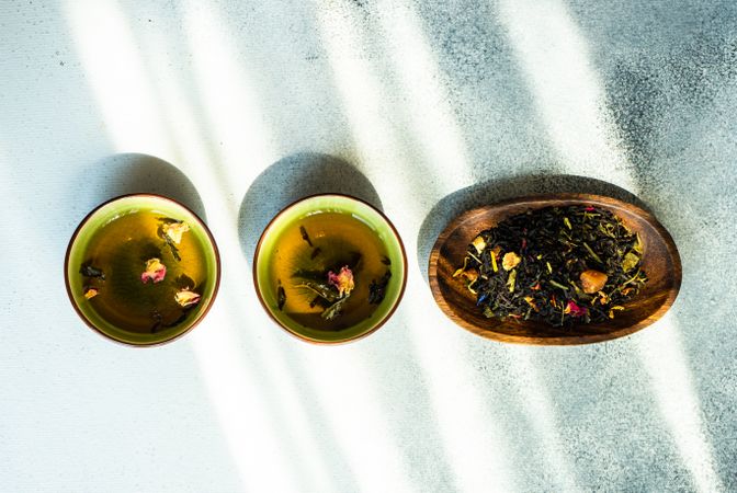 Top view of two cups of green tea and tea leaves