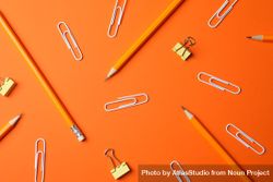 Pencils and paper clips on orange background bDRgE5