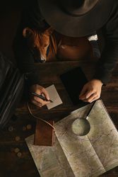 Top view adventure traveler in wide hat writing at desk