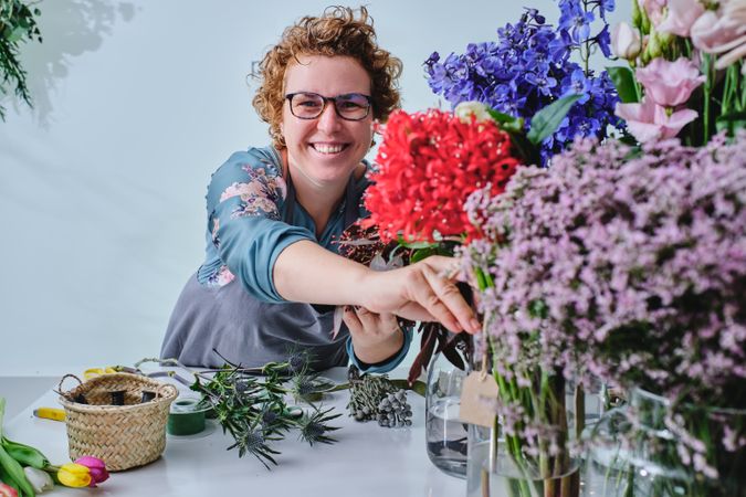 Smiling woman with blooming flowers in floral store