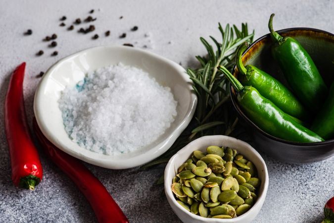 Bowl of salt, pumpkin seeds, pepper surrounded with other fresh ingredients