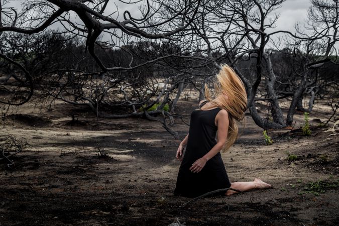 Woman posing on ground near dry trees