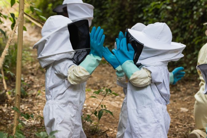 Faceless group of children in protective uniform in apiary