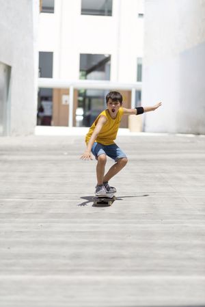 Excited teenage skateboarder riding on the city in a sunny day