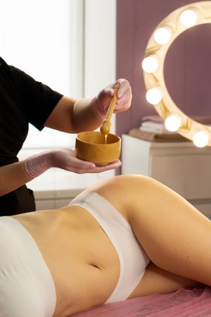 Spa therapist stirring honey mixture before applying to skin.