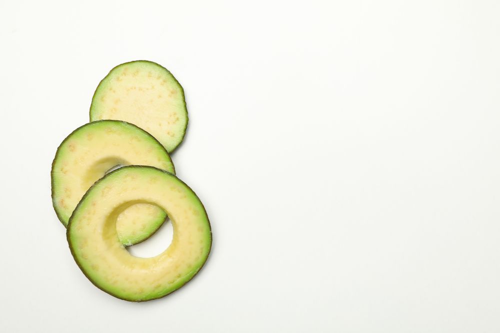 Ripe fresh avocado slices on plain background