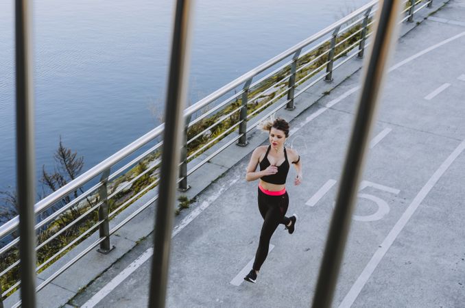 Young woman running on embankment near water