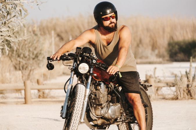 Serious male driving motorcycle in forest