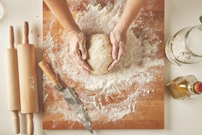Woman forming dough into ball on bread board