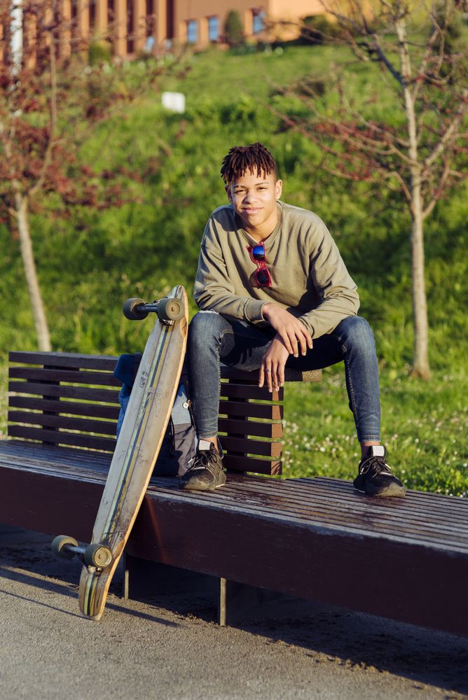 Young Black man sitting on bench with skateboard