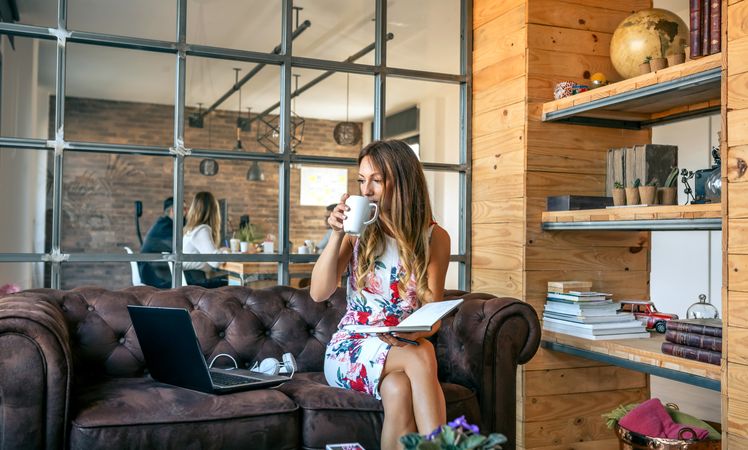 Businesswoman sipping coffee and working in a coworking office
