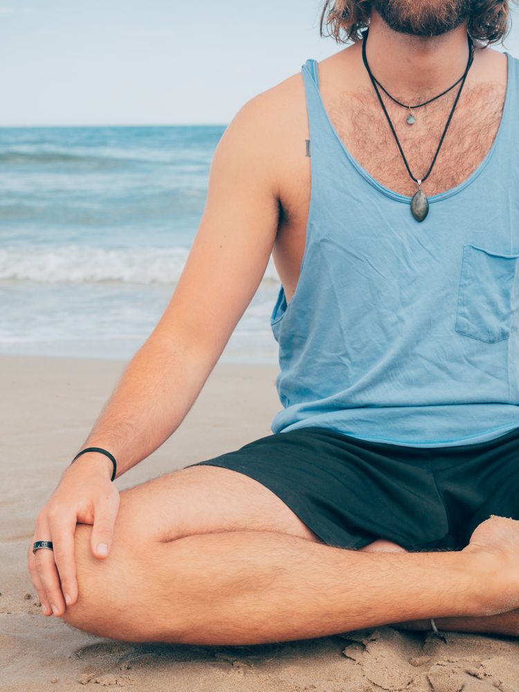 Man training yoga on beach