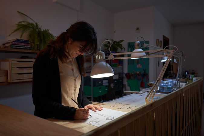 Focused female goldsmith creating images of jewelry