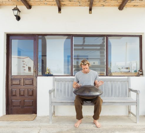 Blond man sitting on bench with big hand drum