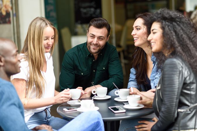Group of male and female friends sipping coffee together at outdoor cafe