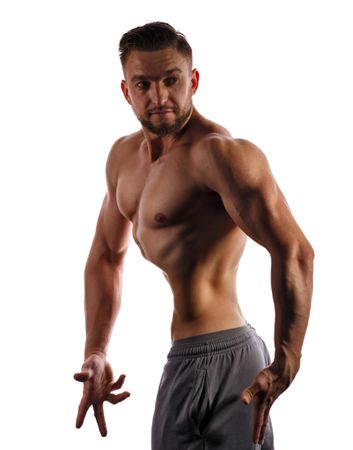 Bodybuilder turned around practicing upper body poses ahead of competition in bright studio