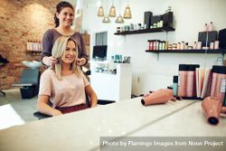 Skilled hairdresser preparing to trim customer’s blonde hair 0LvRX4