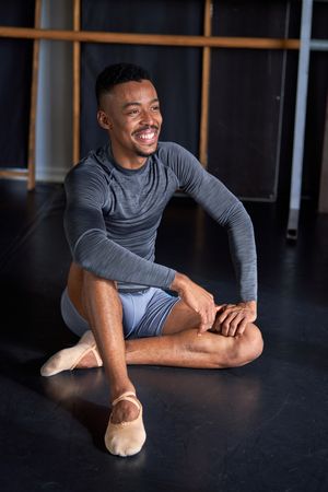 Photo portrait of a Black male with sport clothes and slippers and ballet in a dance academy