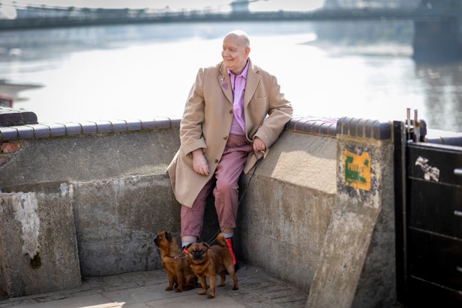 Man leaning on river walk wall with two dogs