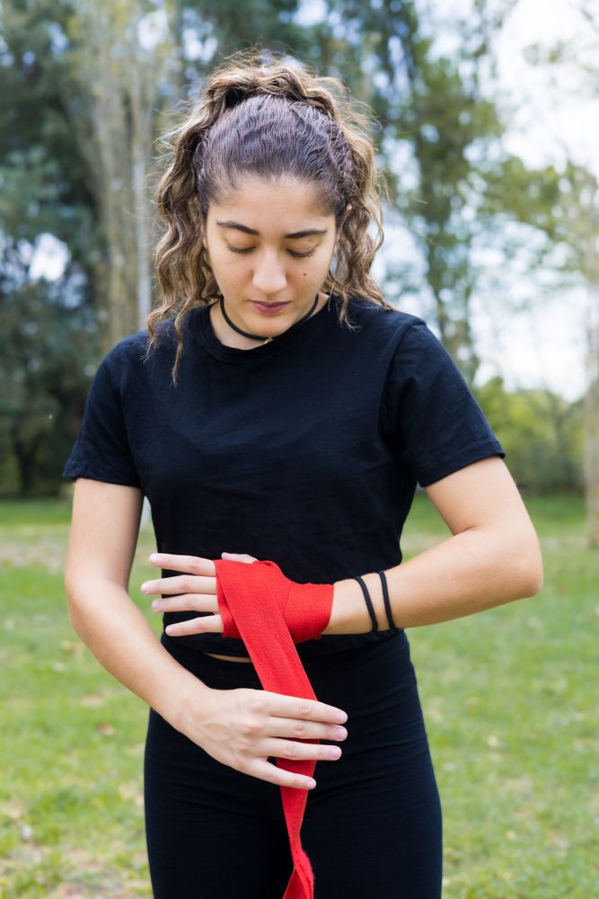 Boxer woman wrapping hands bandage for boxing outdoors