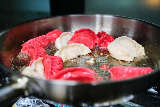 Colorful jiaozi frying in pan on stove