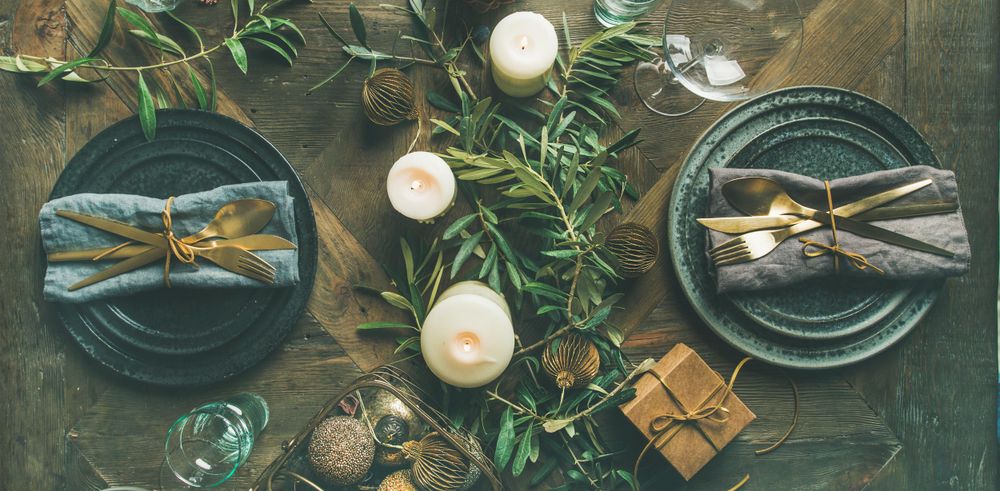 Festival holiday table setting on wooden table, with gold ornaments and branches, wide composition