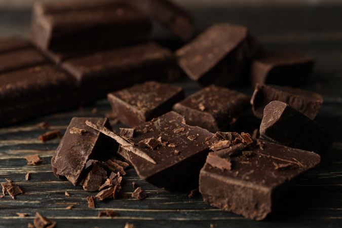 Chocolate pieces on wooden background, close up