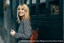 Smiling blonde female wearing casual clothes outdoors with cell phone, copy space 5zo7m4