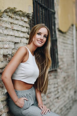 Long haired smiling woman leaning on wall outside