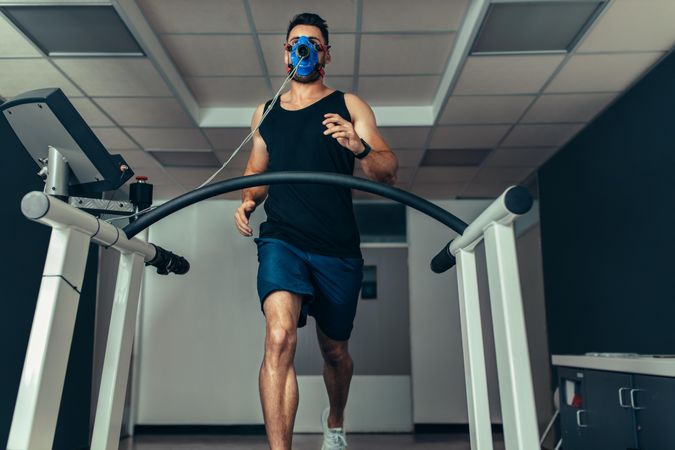 Runner with mask running on treadmill machine and testing performance