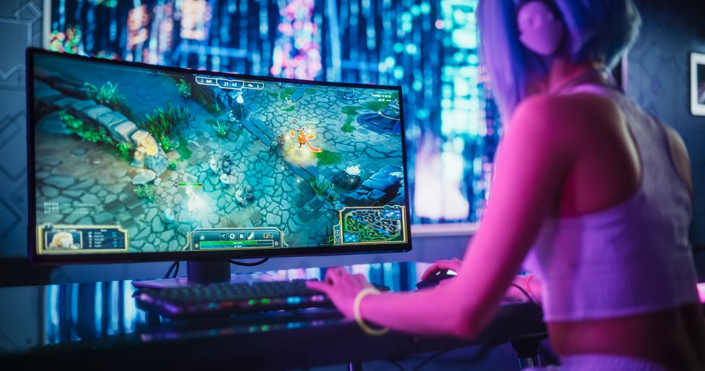 Young Female Gamer Playing Strategy Video Game with Modern Graphics on Her Computer.