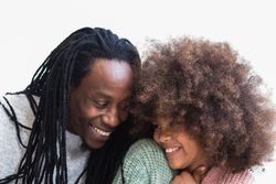 Delighted Black man cuddling with daughter