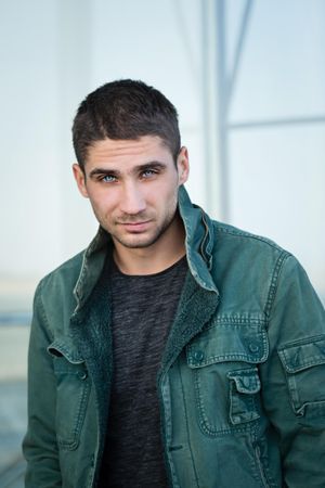 Male in green jacket and bright blue eyes looking into camera