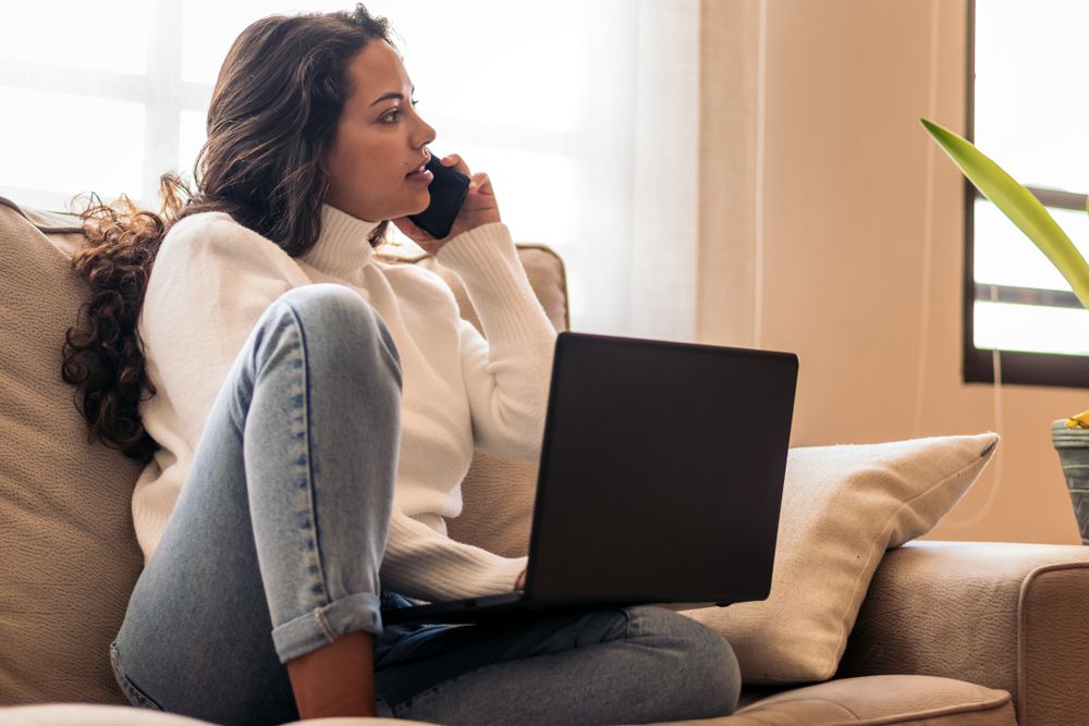 Remote Work and Communication: Young Woman Using Laptop and Smart Phone at home
