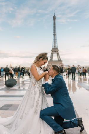 Bridegroom kneeling and kissing hands of bride