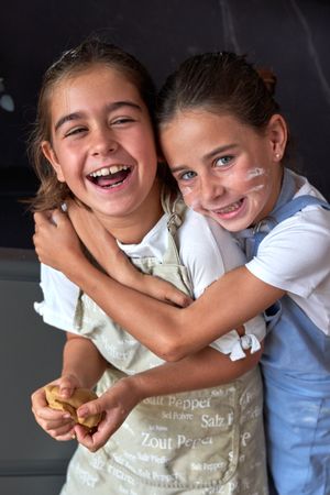 Glad girl hugging friend while cooking together