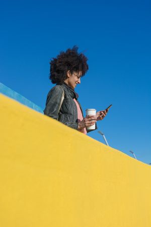Black woman with afro hair leaning against brightly colored wall