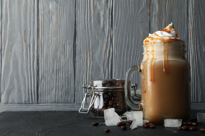 Iced coffee with poured cream on gray wooden background