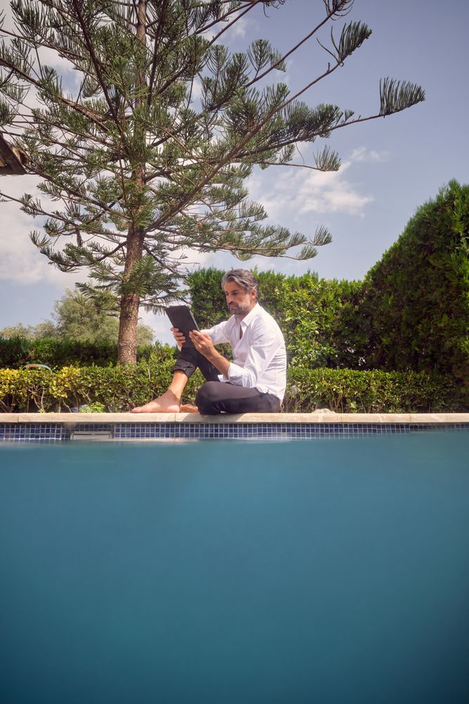 Man browsing tablet at poolside
